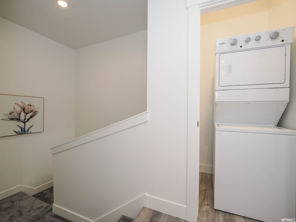 Laundry room featuring stacked washer / dryer and wood-type flooring