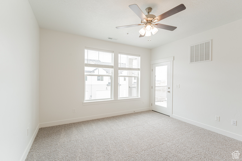 Empty room with ceiling fan, light carpet, and a healthy amount of sunlight