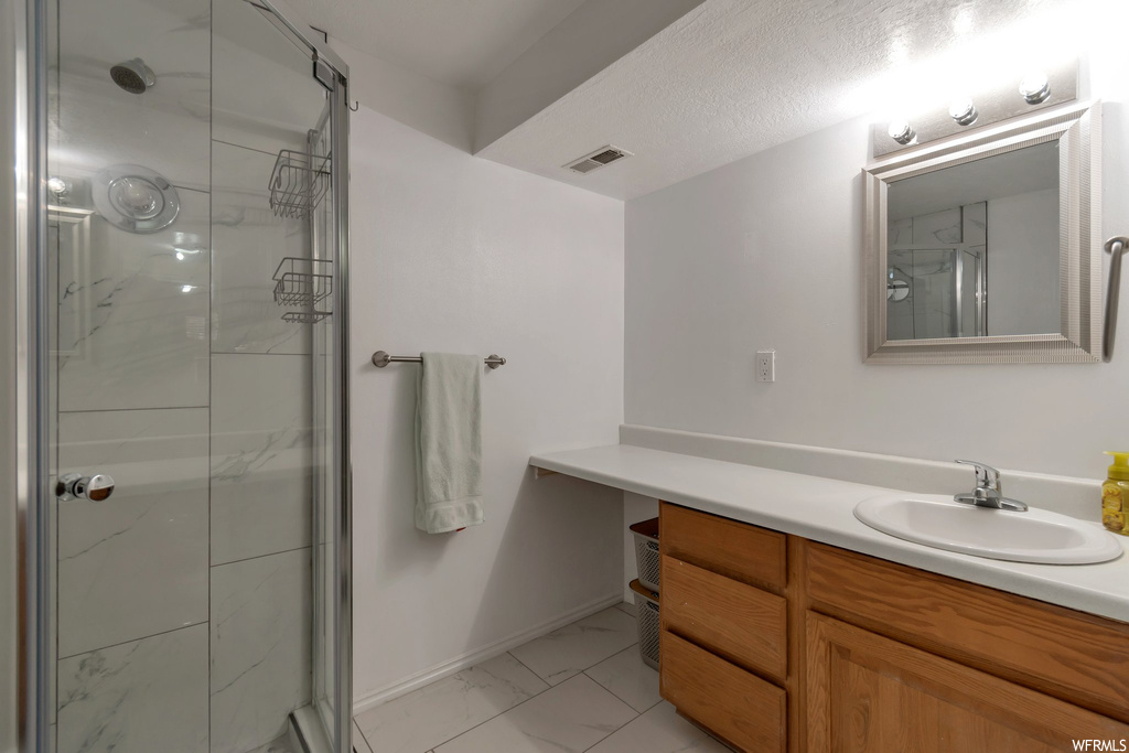 Bathroom featuring tile flooring, a shower with door, a textured ceiling, and vanity