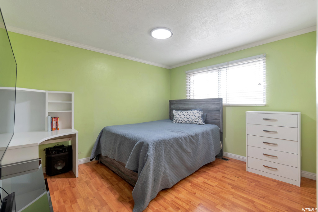 Bedroom with crown molding and light hardwood / wood-style floors