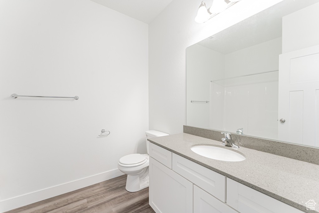 Bathroom with toilet, hardwood / wood-style floors, and vanity