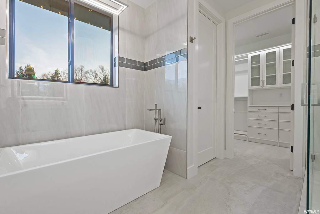 Bathroom with tile floors, tile walls, and a bathtub
