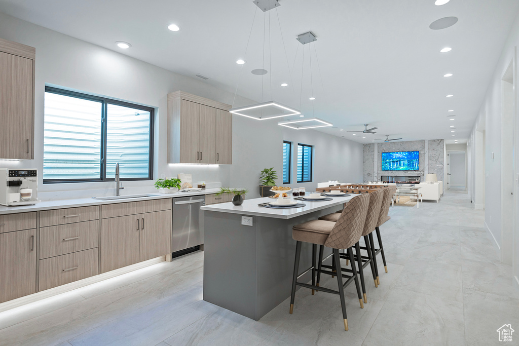 Kitchen featuring dishwasher, a breakfast bar area, hanging light fixtures, a center island, and sink