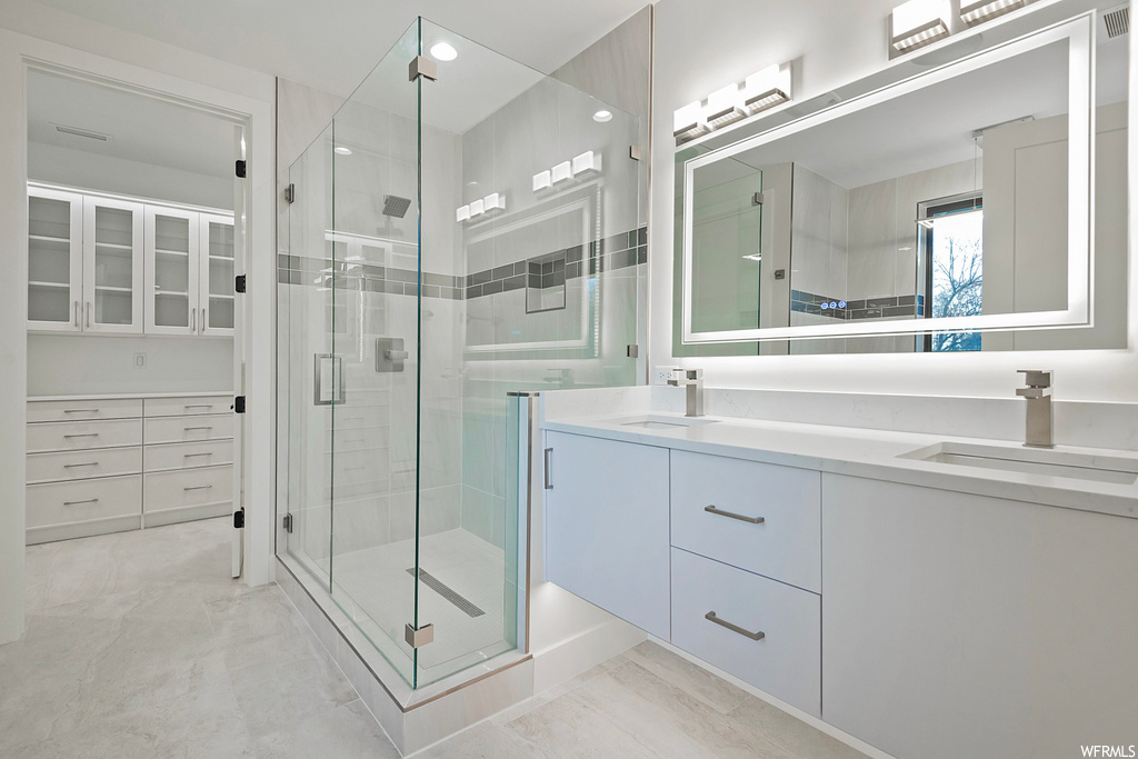 Bathroom featuring a shower with shower door, tile flooring, and dual bowl vanity