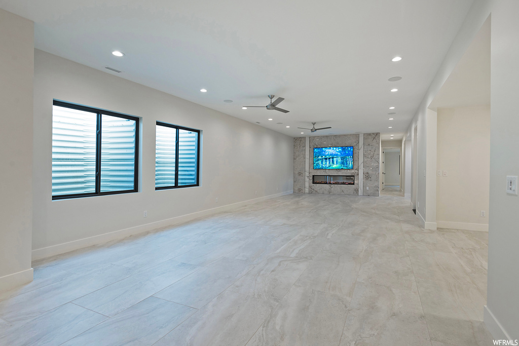 Unfurnished living room featuring ceiling fan and light tile floors