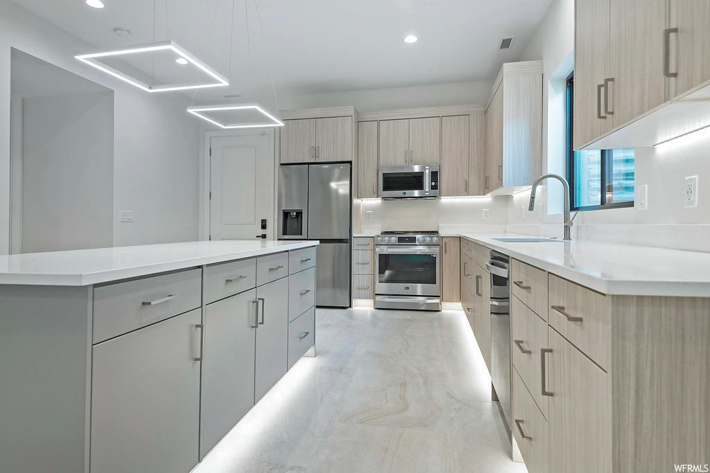Kitchen with sink, a center island, stainless steel appliances, gray cabinets, and light brown cabinetry
