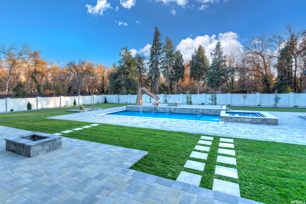 View of yard with a swimming pool with hot tub, a patio area, and a fire pit