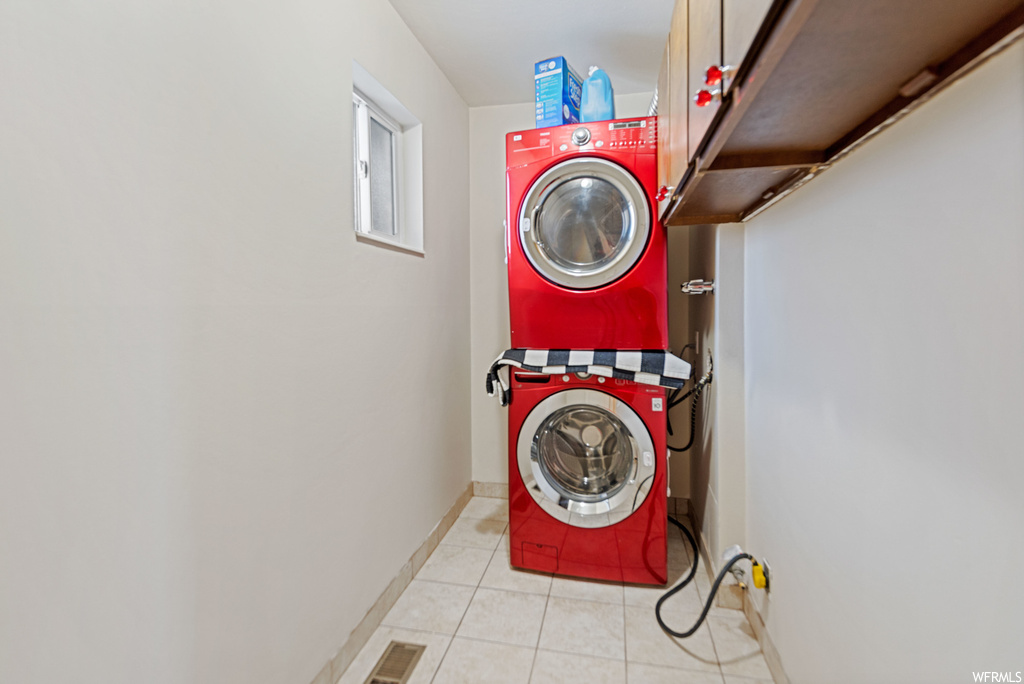 Laundry area with light tile floors and stacked washer and dryer