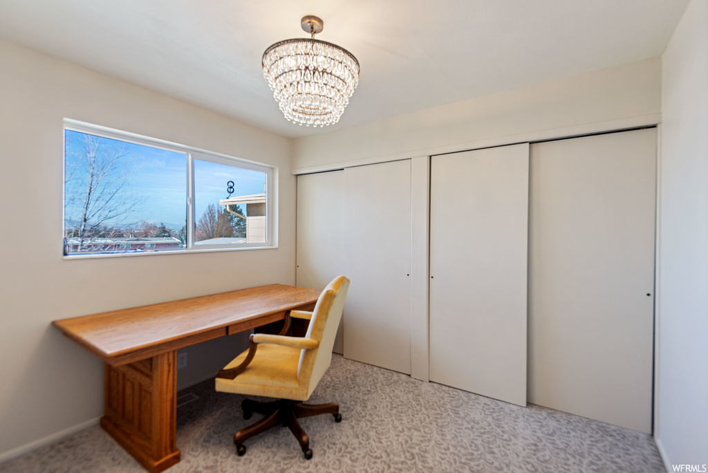 Office area featuring an inviting chandelier and light carpet