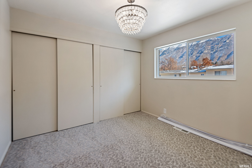 Unfurnished bedroom with a closet, a chandelier, and light colored carpet