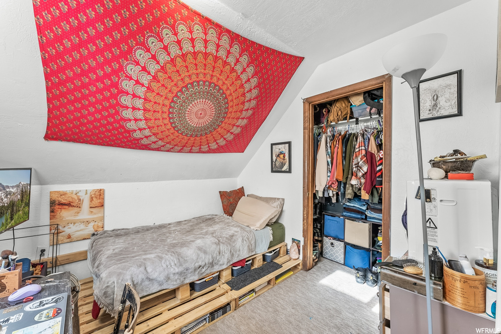 Bedroom with lofted ceiling, a closet, and light carpet