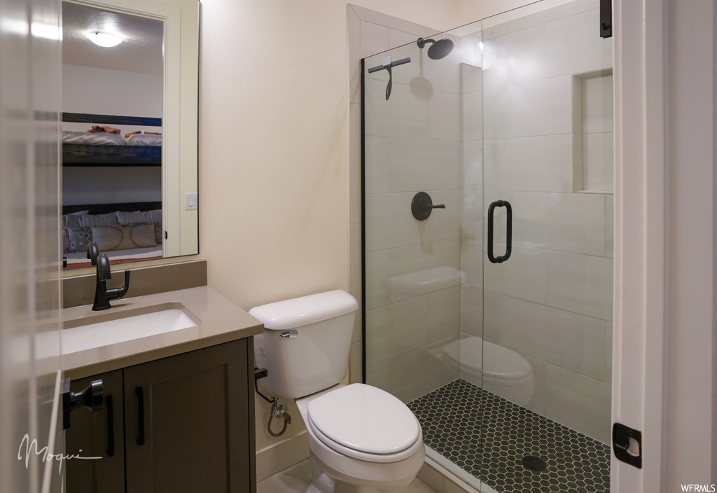 Bathroom featuring toilet, a shower with door, and vanity with extensive cabinet space