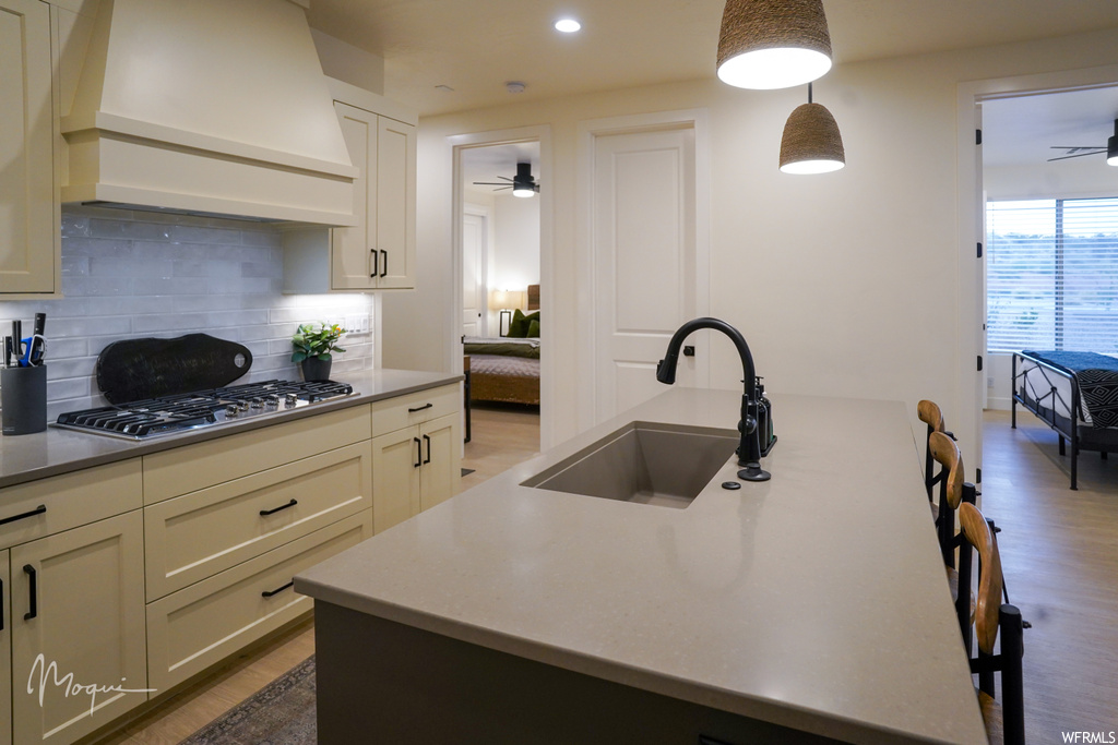 Kitchen featuring sink, premium range hood, pendant lighting, tasteful backsplash, and stainless steel gas cooktop