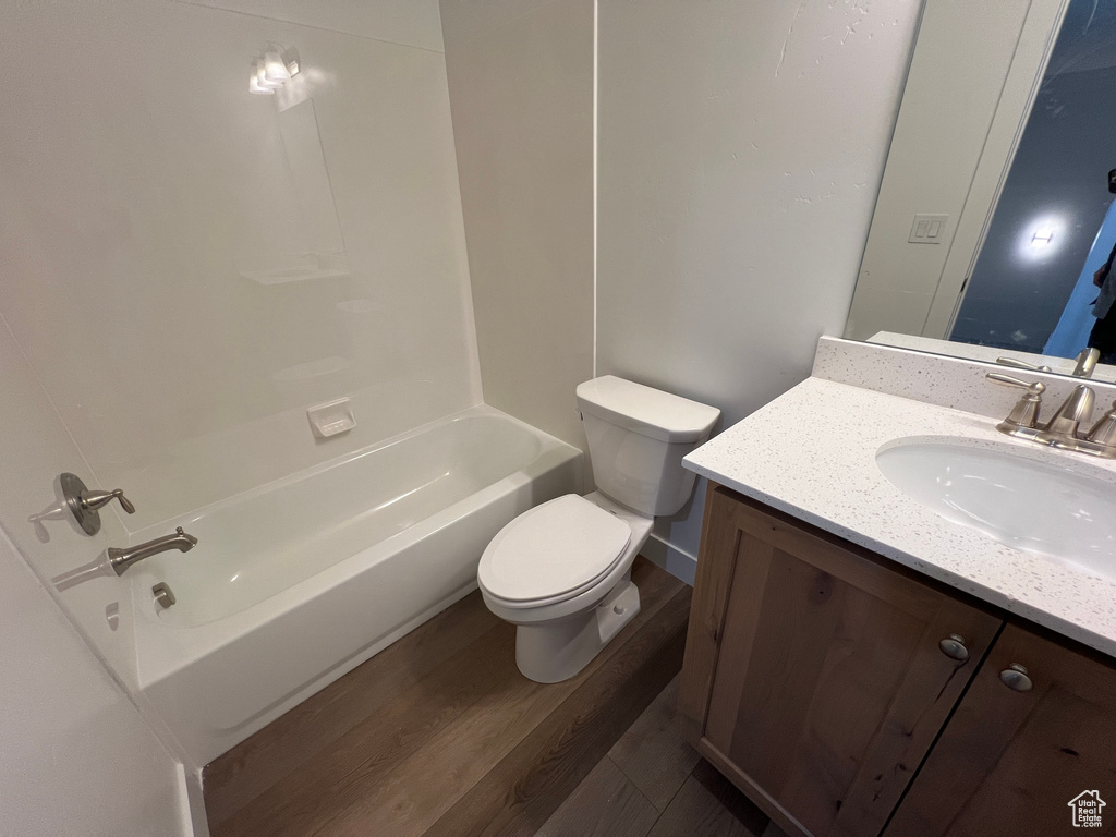Full bathroom with vanity, toilet, hardwood / wood-style flooring, and shower / bathing tub combination