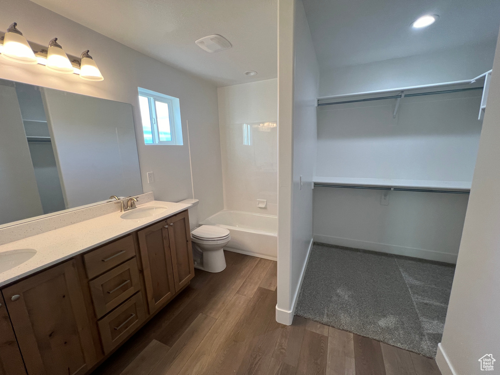 Full bathroom featuring double vanity, toilet, hardwood / wood-style flooring, and bathtub / shower combination