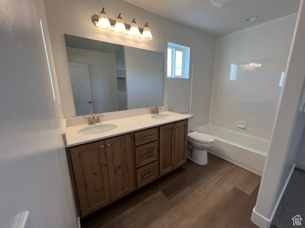 Full bathroom with dual sinks,  shower combination, oversized vanity, toilet, and wood-type flooring