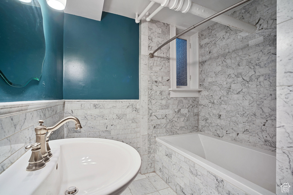 Bathroom featuring tile walls, tile floors, sink, and tiled shower / bath