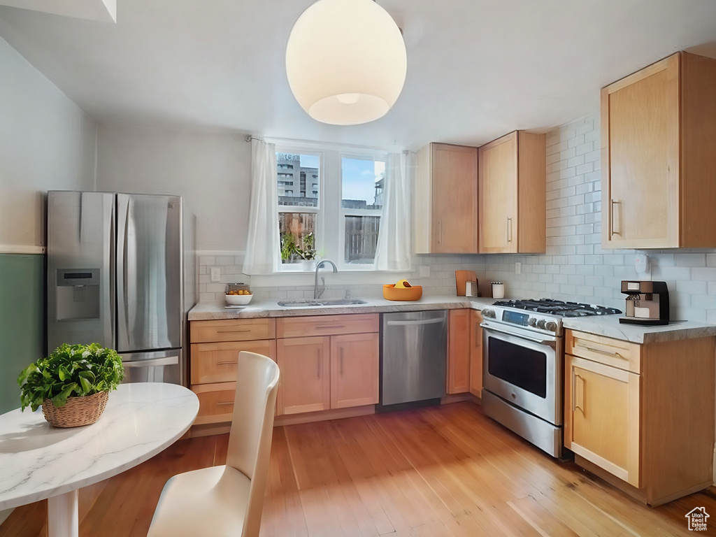 Kitchen featuring light hardwood / wood-style flooring, tasteful backsplash, stainless steel appliances, and light brown cabinets