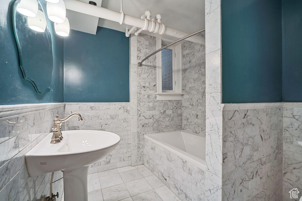 Bathroom with tiled shower / bath combo, tile flooring, tasteful backsplash, and tile walls