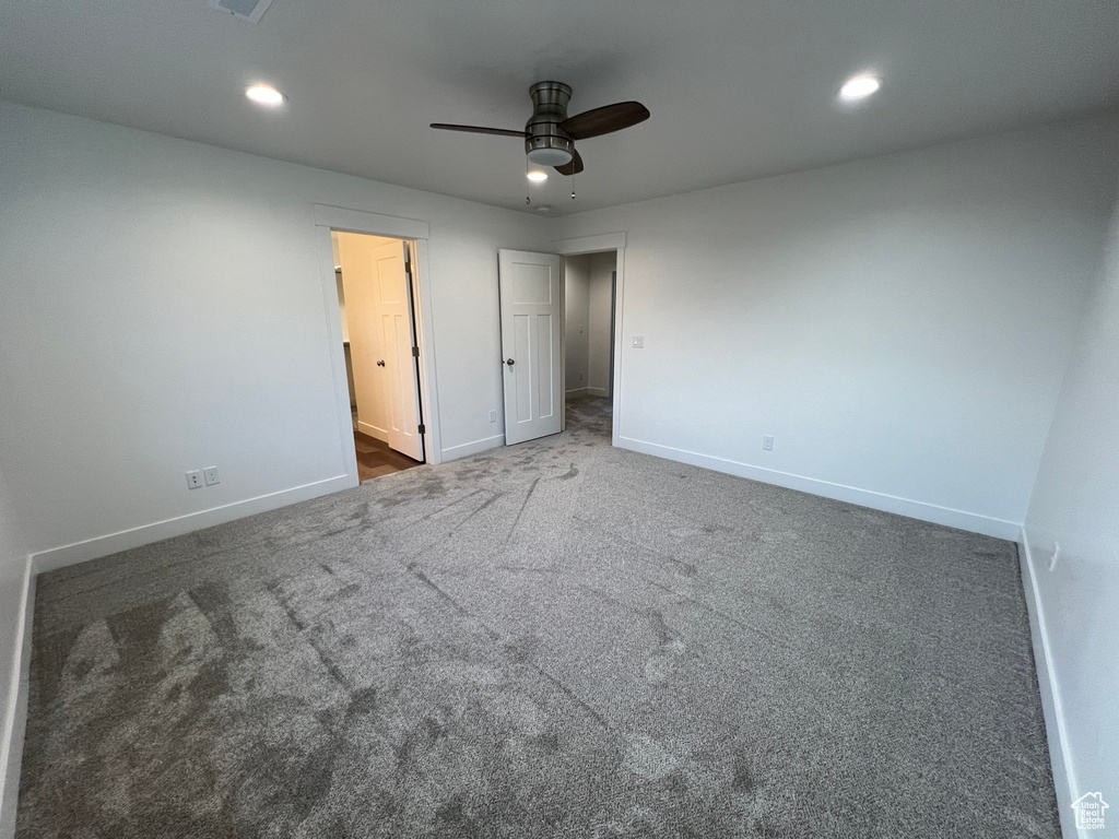 Unfurnished bedroom featuring ceiling fan, carpet flooring, and ensuite bath