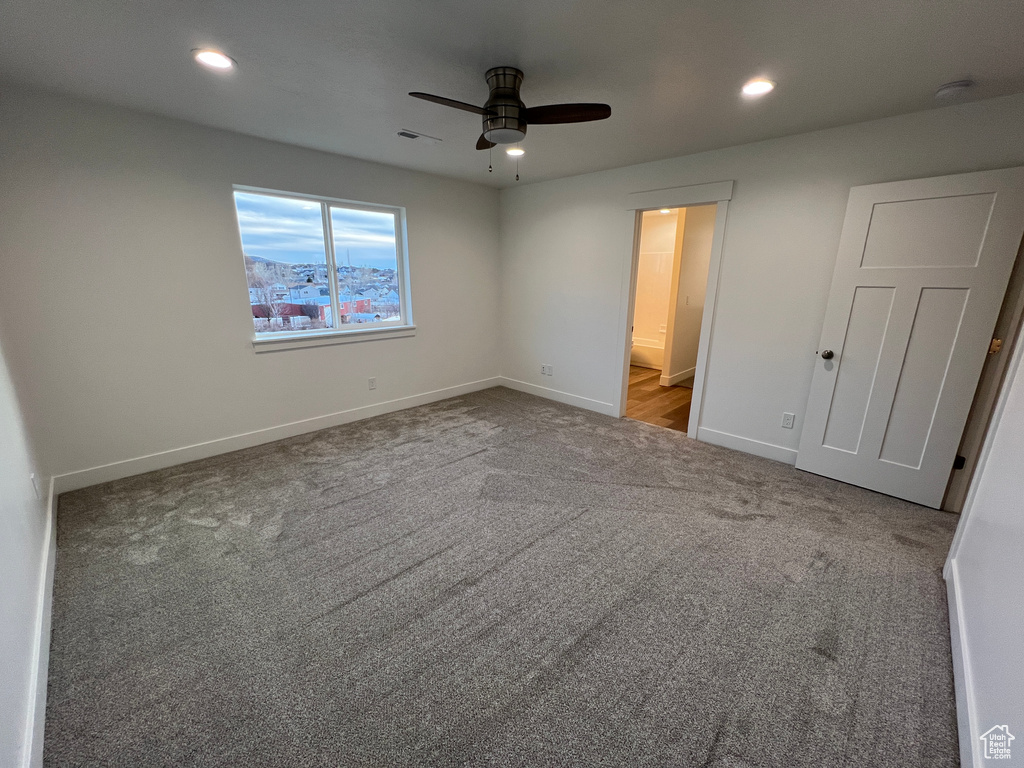 Unfurnished bedroom featuring connected bathroom, ceiling fan, and light colored carpet