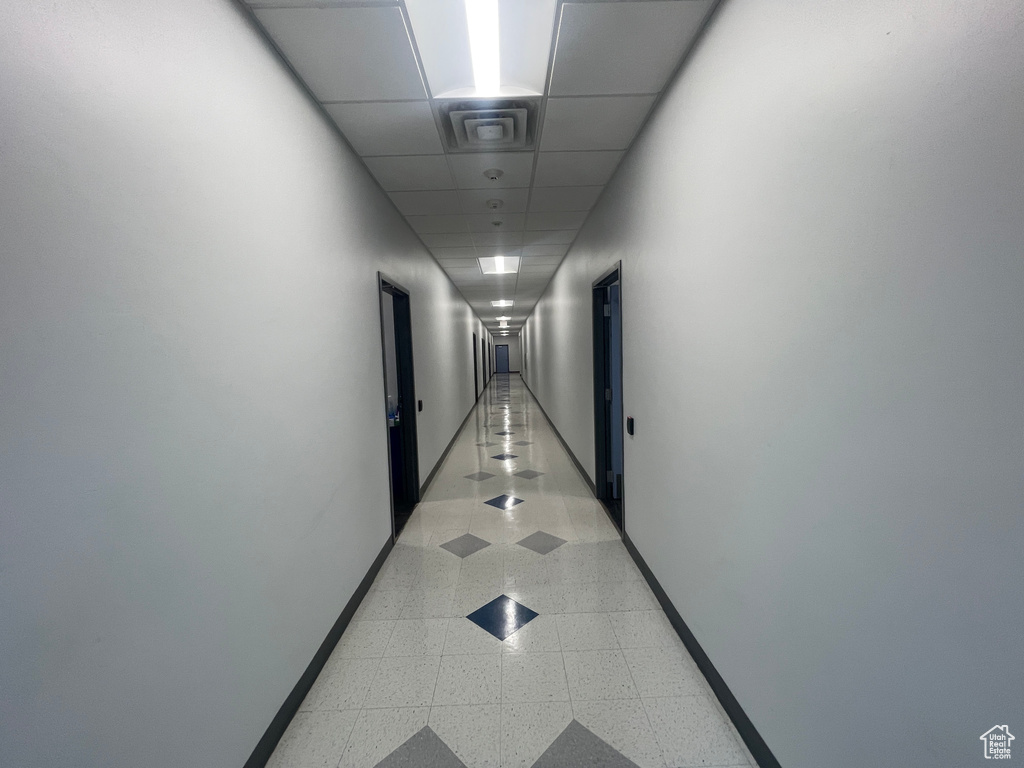 Hall with a paneled ceiling and dark aggregate flooring