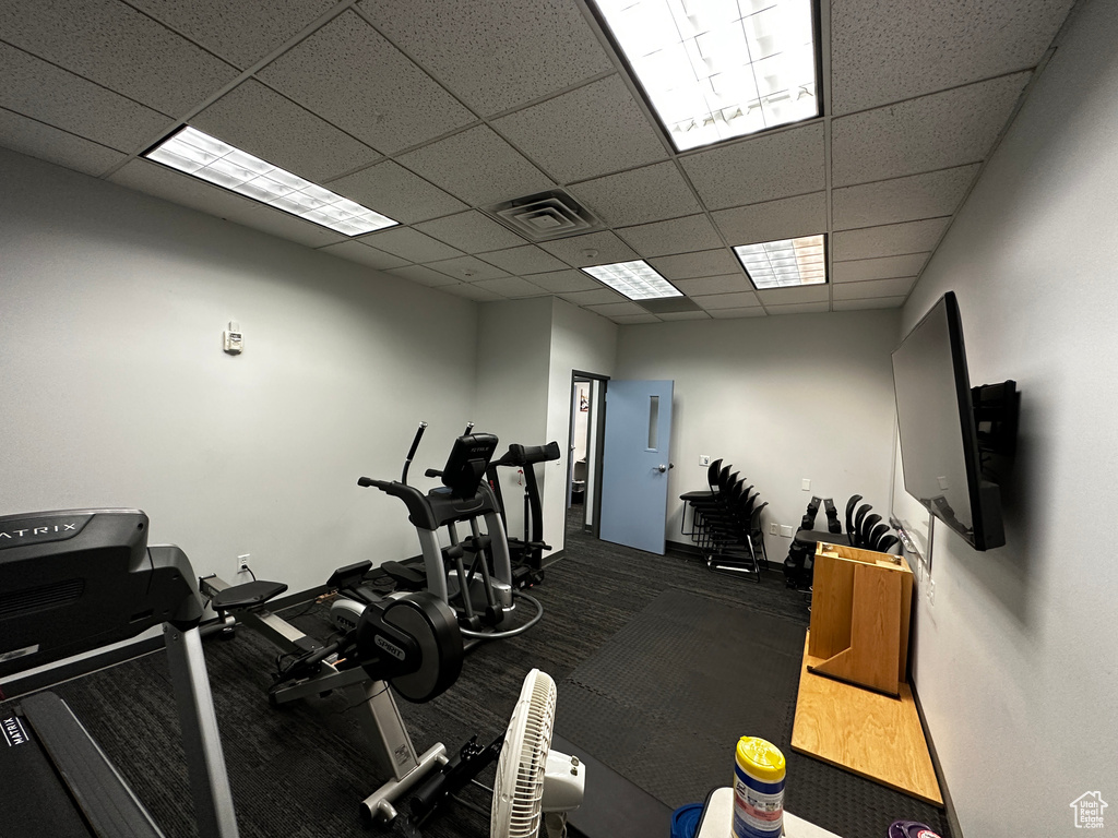 Workout area with a drop ceiling and baseboards
