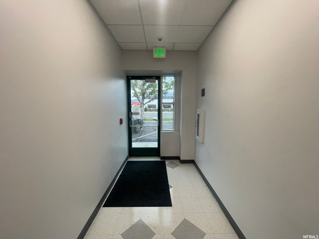 Doorway with a paneled ceiling and light tile flooring