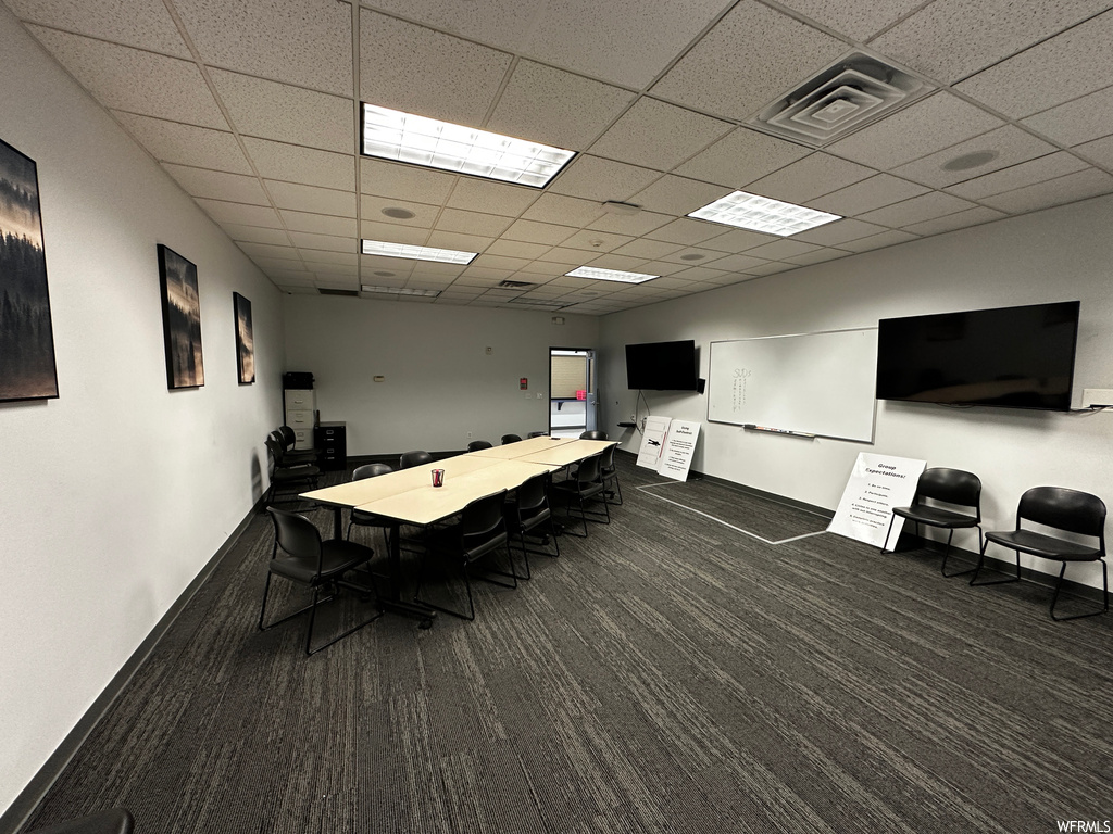 Office featuring dark carpet and a paneled ceiling