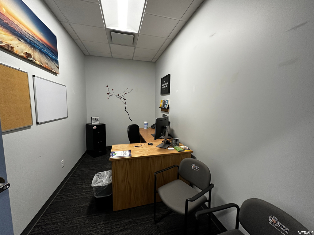 Office space with dark carpet and a drop ceiling