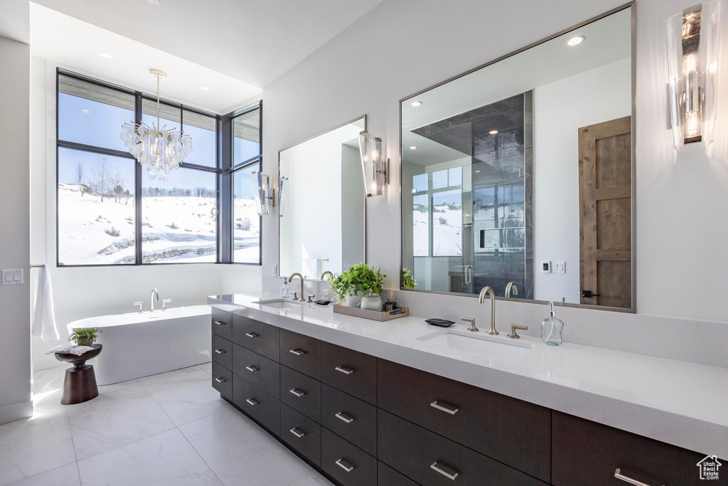 Bathroom featuring tile floors, a wealth of natural light, large vanity, and a chandelier