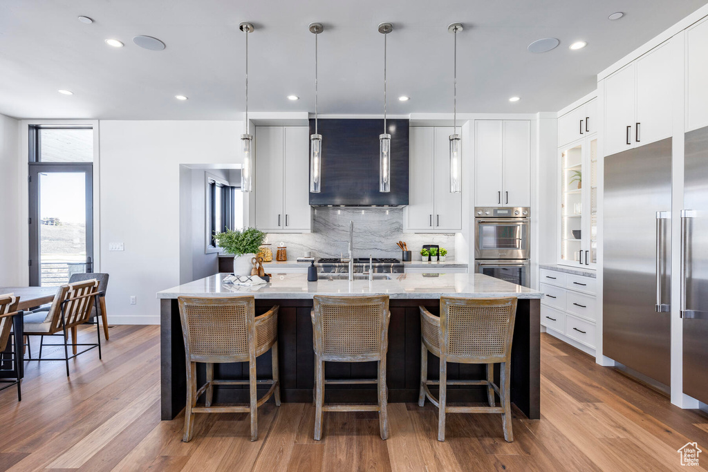 Kitchen with pendant lighting, white cabinets, and light hardwood / wood-style floors