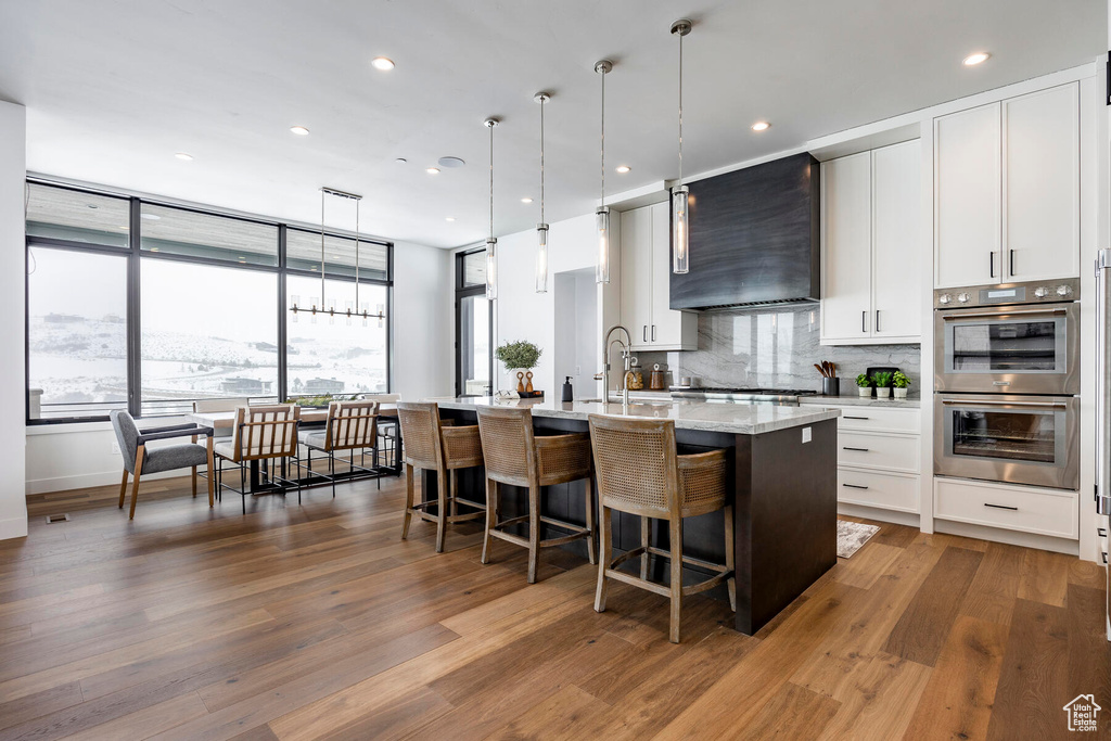 Kitchen featuring decorative light fixtures, wall chimney exhaust hood, dark hardwood / wood-style flooring, and appliances with stainless steel finishes