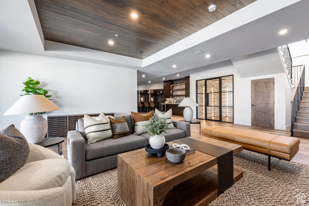 Living room featuring a raised ceiling, light wood-type flooring, and wooden ceiling