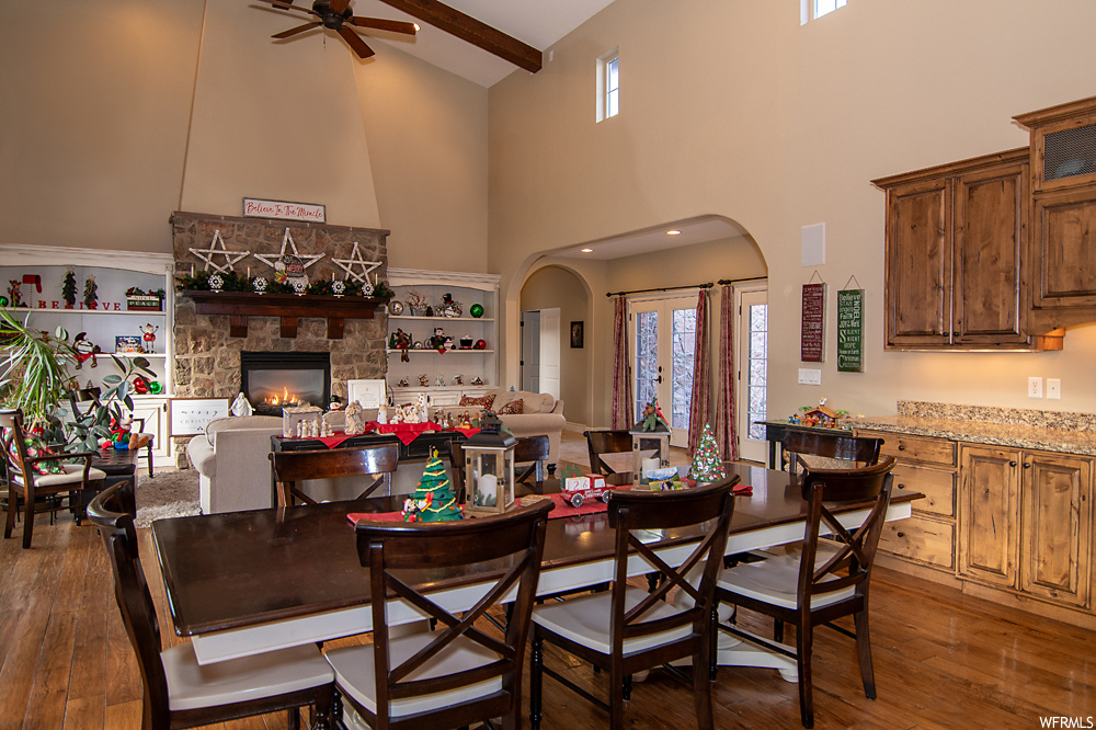 Dining room with dark hardwood / wood-style floors, ceiling fan, a fireplace, and high vaulted ceiling