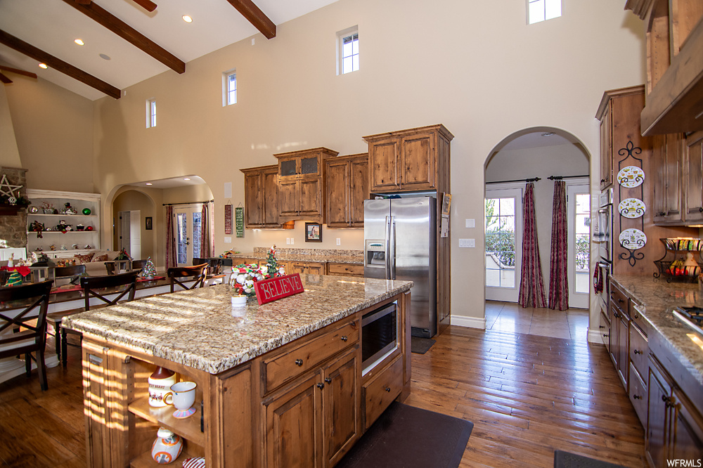 Kitchen with a center island, beam ceiling, high vaulted ceiling, and stainless steel appliances