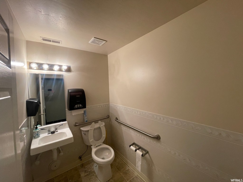 Bathroom with toilet, sink, and tile flooring