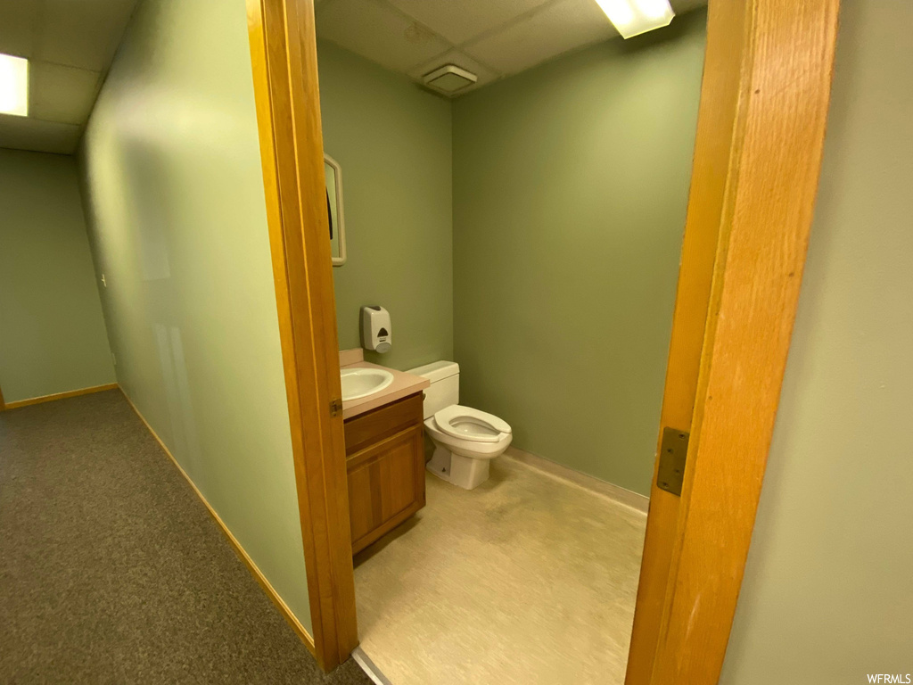 Bathroom with toilet, a paneled ceiling, and vanity