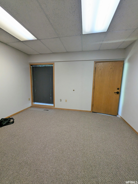 Unfurnished room featuring a drop ceiling and light carpet