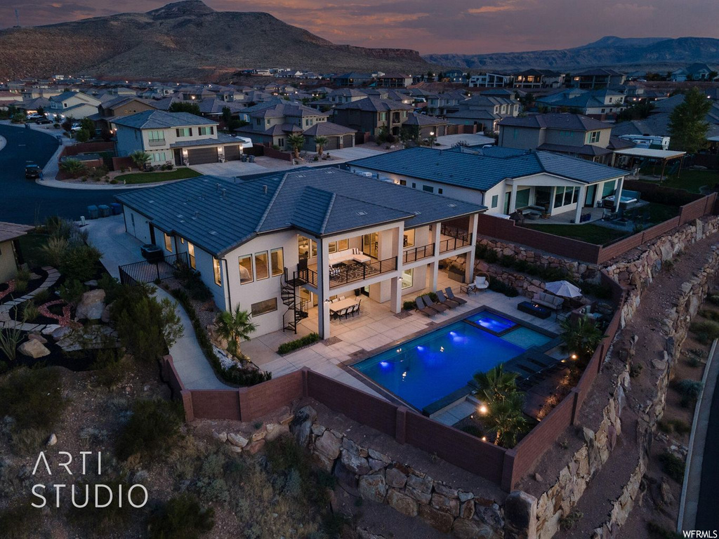 Pool at dusk with a patio area and a mountain view