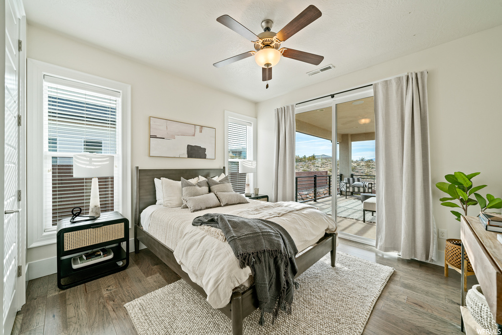 Bedroom with dark hardwood / wood-style flooring, ceiling fan, and access to exterior