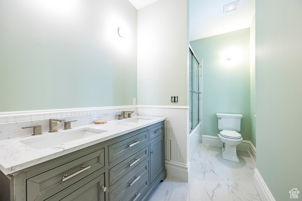 Full bathroom with bath / shower combo with glass door, vanity, and toilet