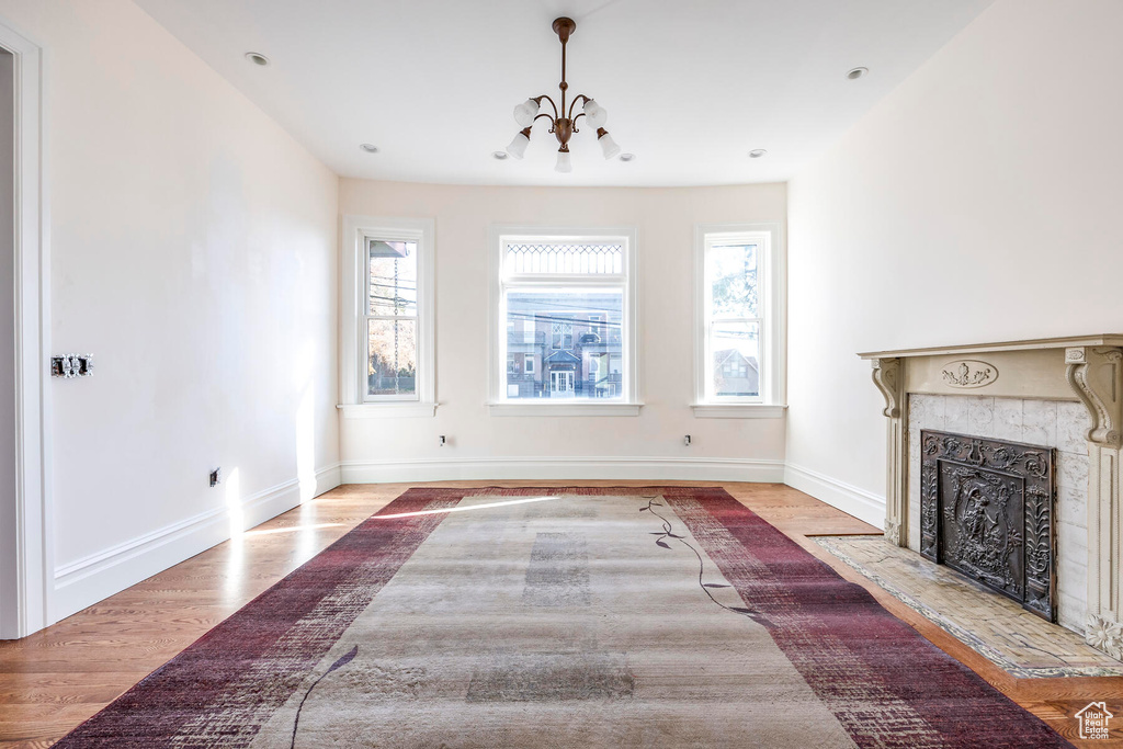 Unfurnished living room featuring light wood-type flooring, a chandelier, and a wealth of natural light