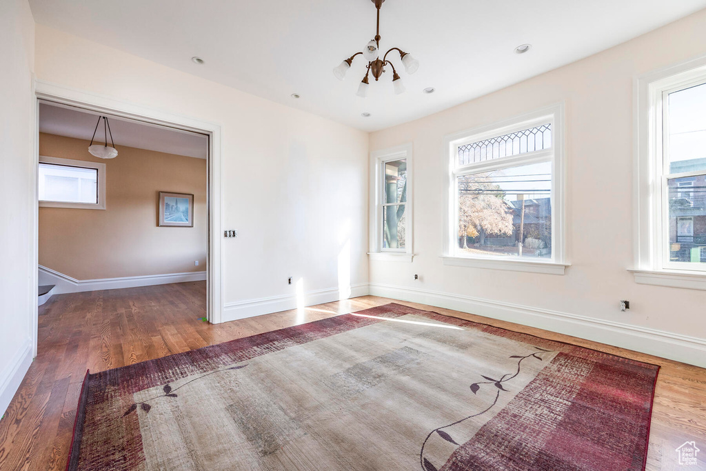 Unfurnished living room with hardwood / wood-style floors and a chandelier