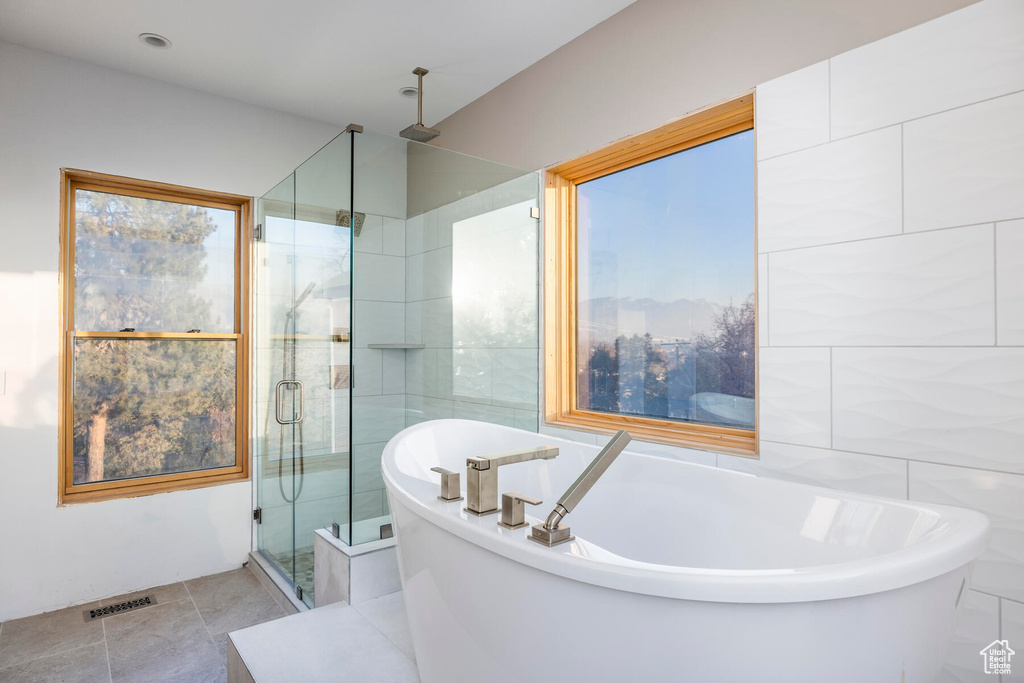 Bathroom with shower with separate bathtub and tile patterned floors