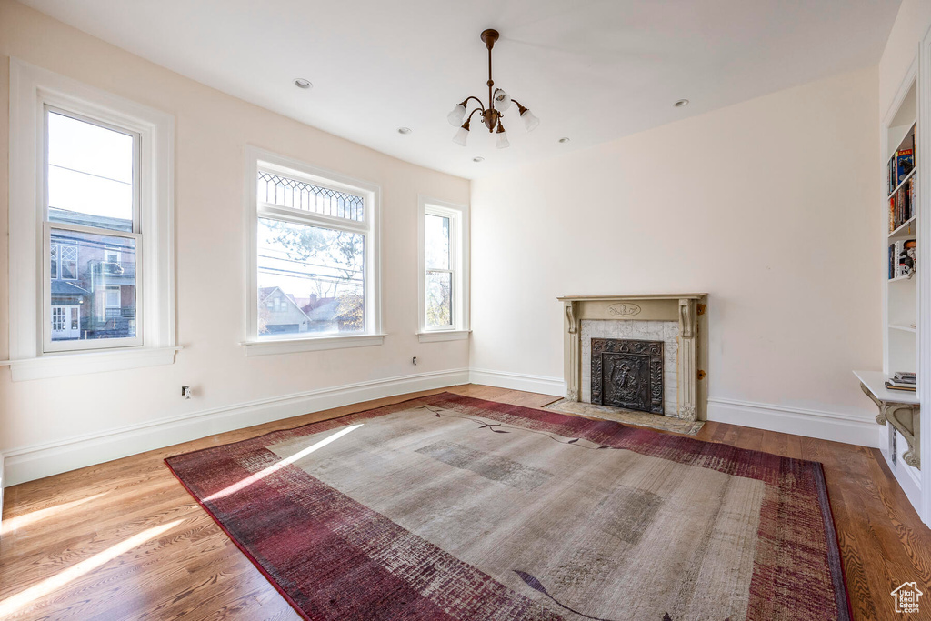 Unfurnished living room featuring a notable chandelier, light hardwood / wood-style flooring, and a high end fireplace