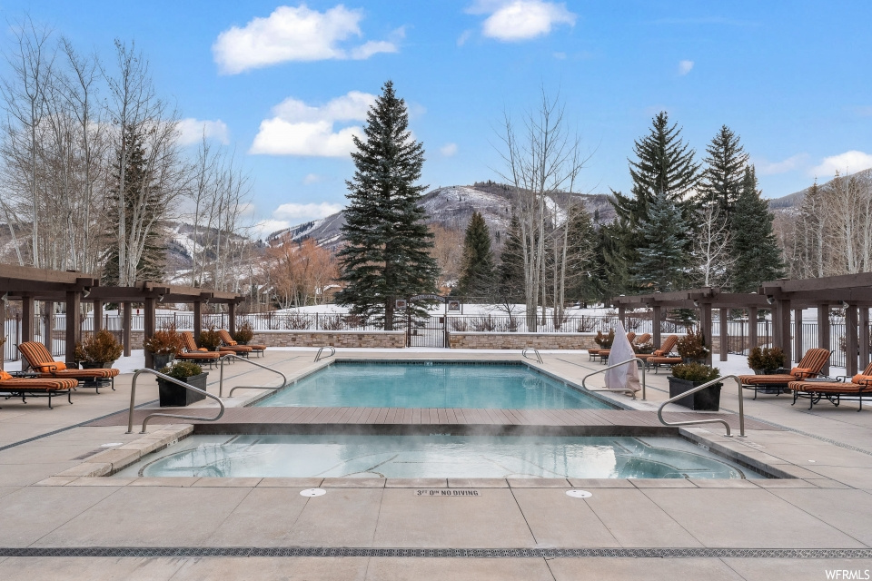 Snow covered pool with a patio area and a mountain view
