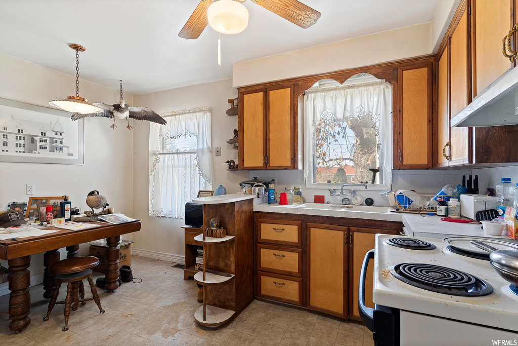 Kitchen featuring light tile floors, wall chimney range hood, white stove, pendant lighting, and ceiling fan
