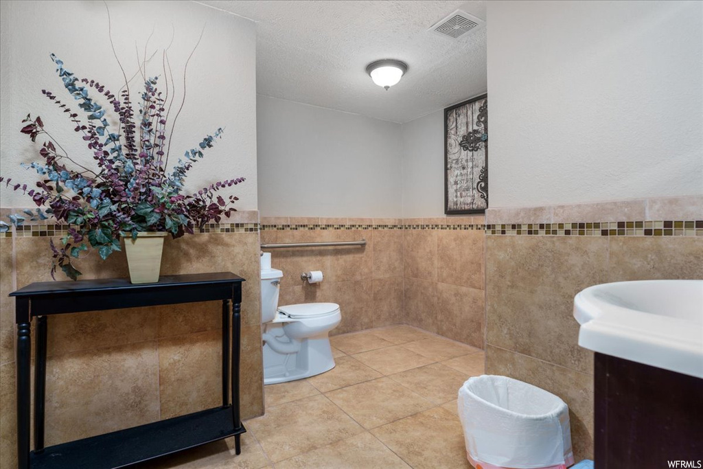 Bathroom featuring toilet, tile walls, a textured ceiling, tile flooring, and vanity