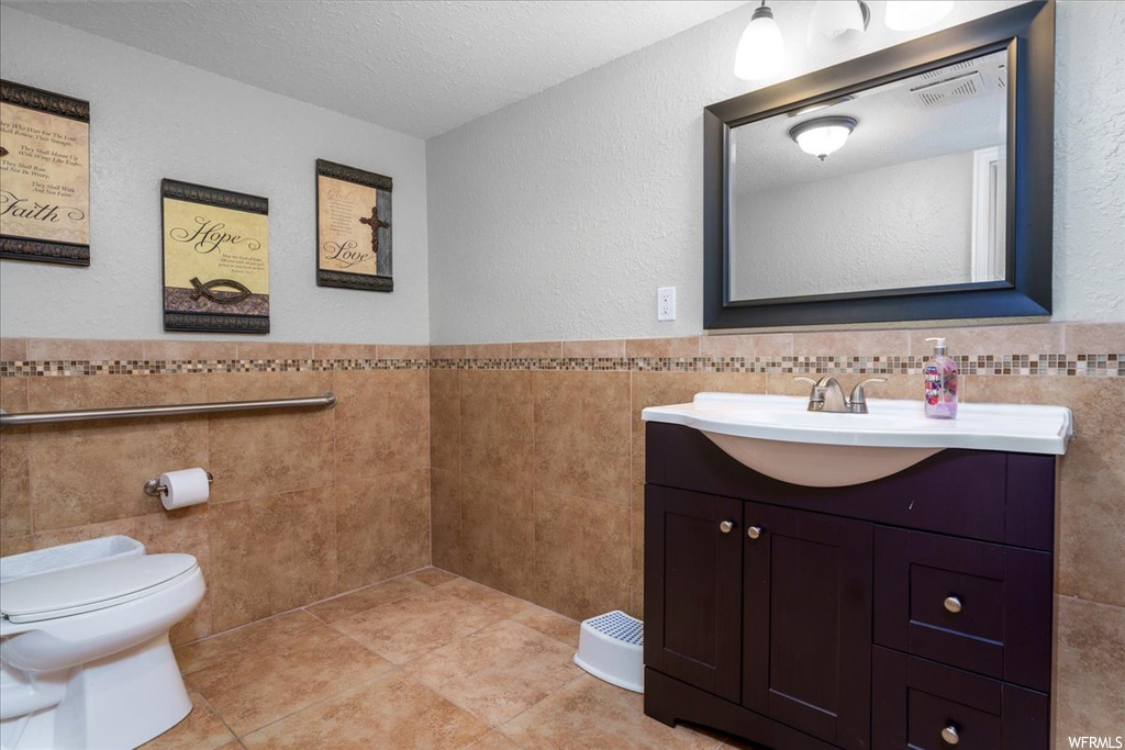 Bathroom with vanity, toilet, tile walls, and tile flooring